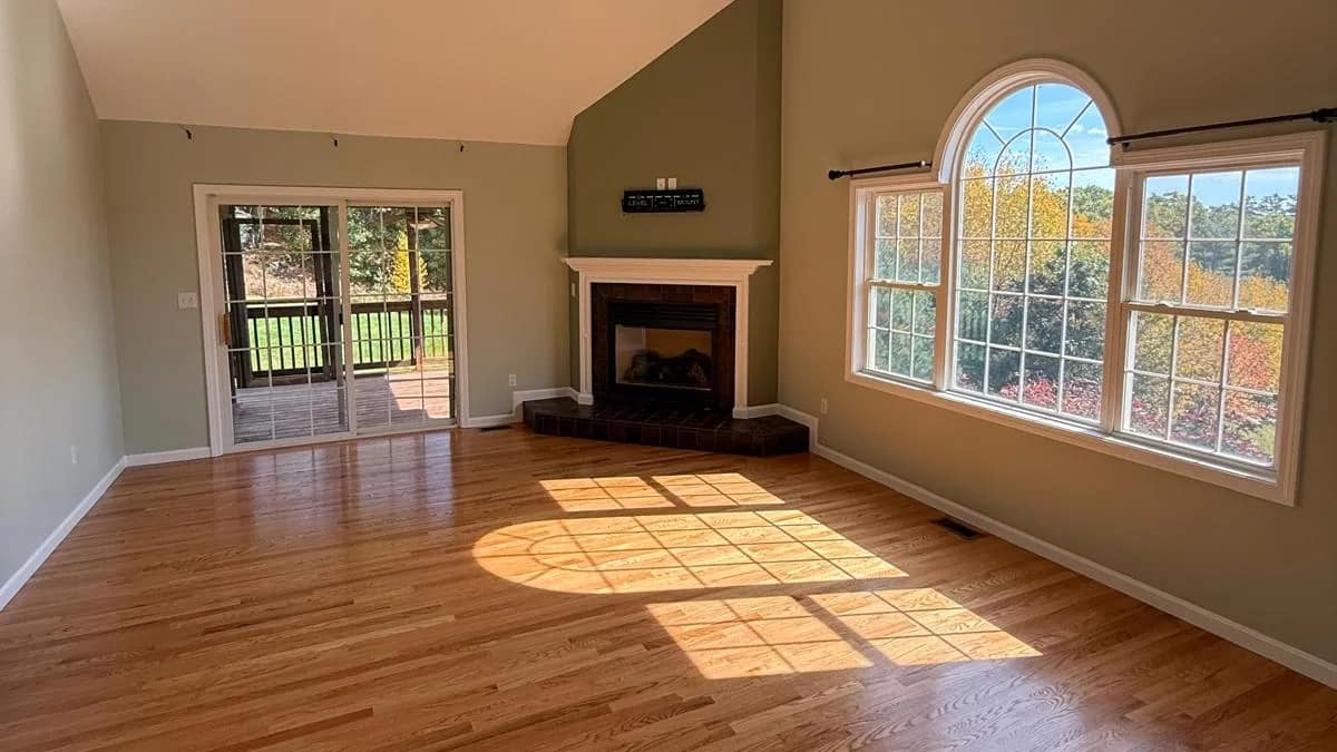 Living room of a Douglas, Massachusetts home after an interior repaint by JH Painting Services, sage and greige walls under a vaulted ceiling with an arched window
