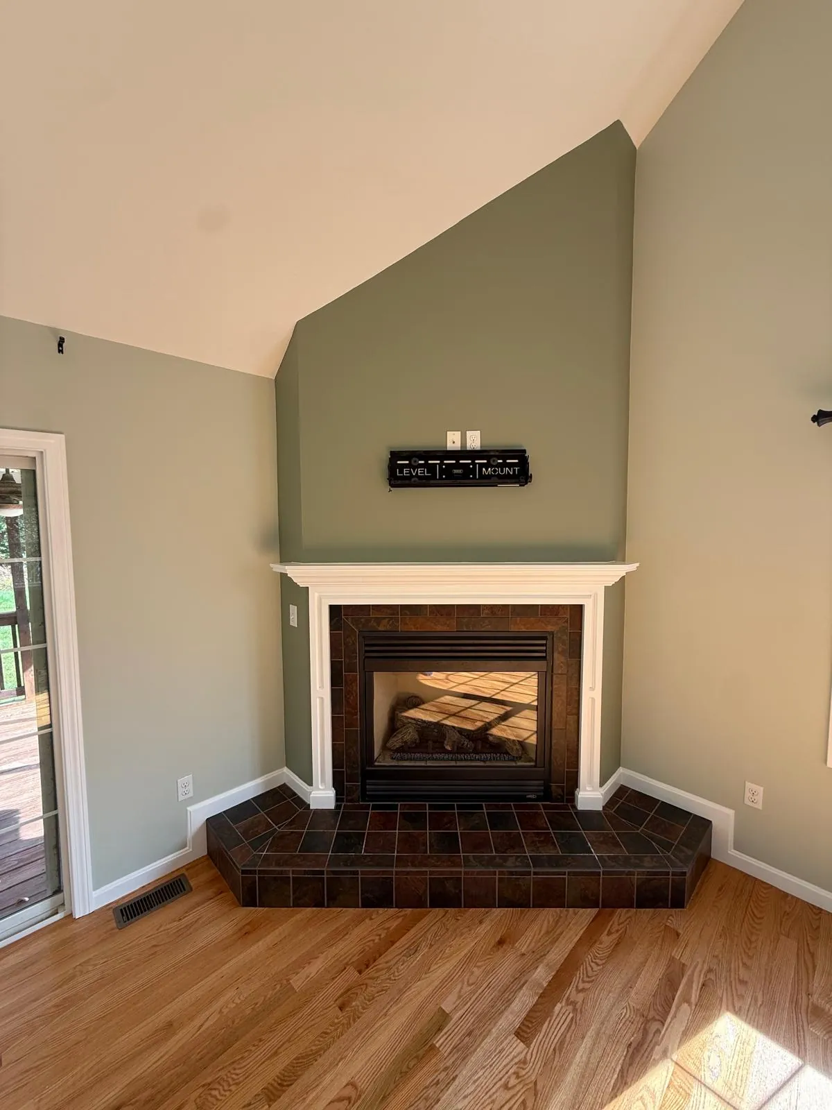 Interior Painting in Douglas, MA by JH Painting Services, after: Fireplace wall: the dark brown accent repainted sage green. Before frame taken from the crew's walkthrough video.