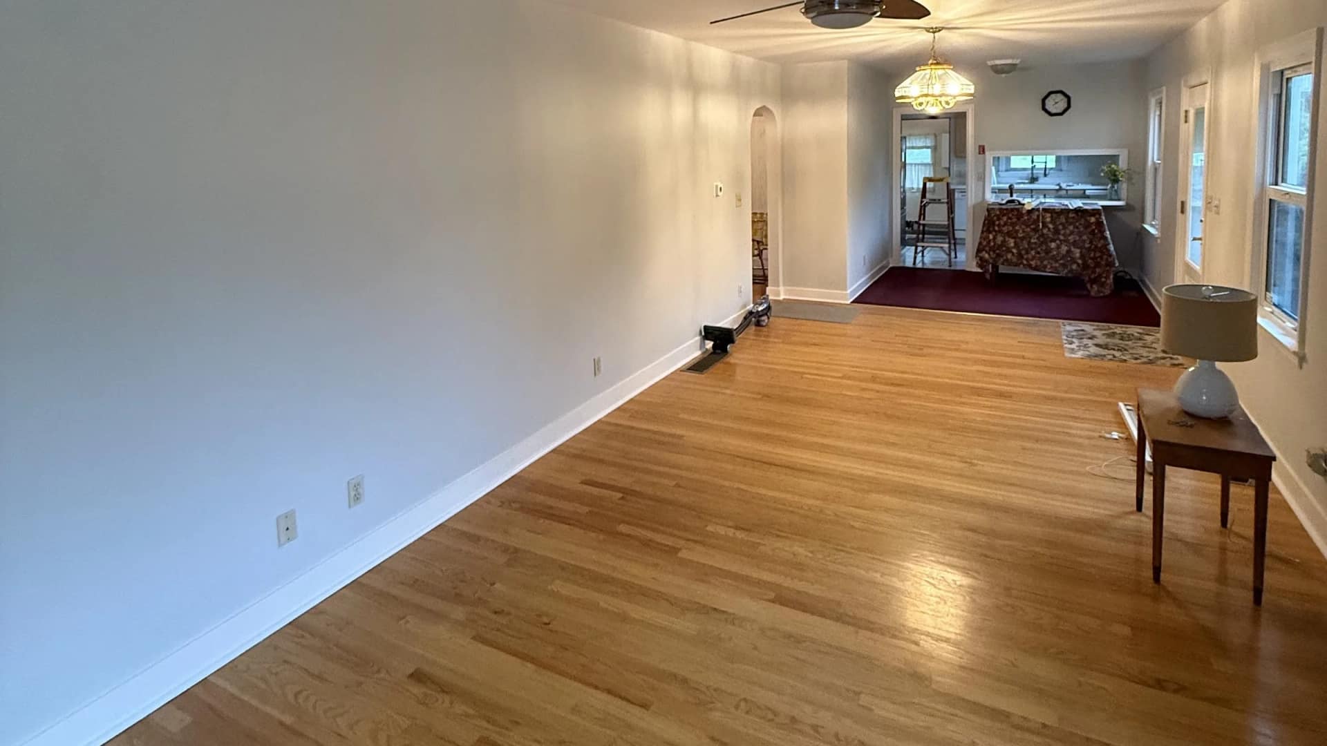 Living and dining room of a Southbridge, Massachusetts home after an interior repaint by JH Painting Services, with fresh walls, white trim and refinished hardwood floors